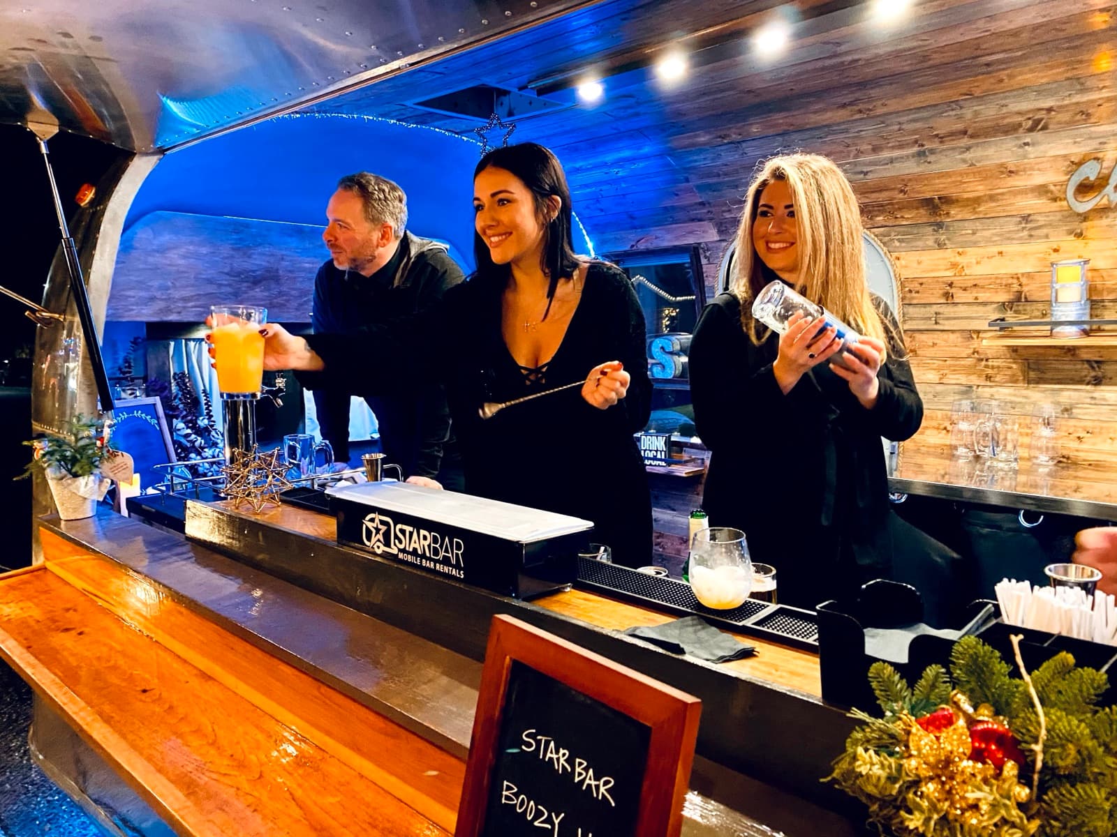 The STARBAR NY team serving cocktails behind the Airstream mobile bar